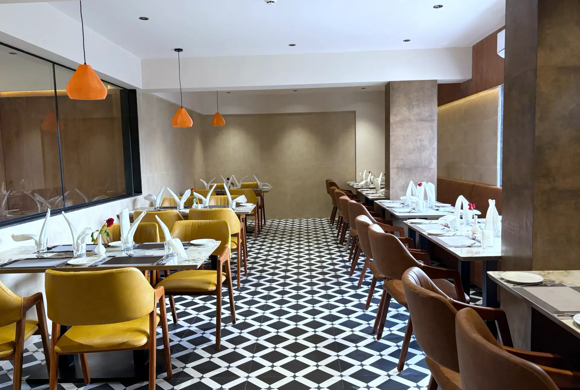 The restaurant laid for service, patterned floor and pendant lights above set tables